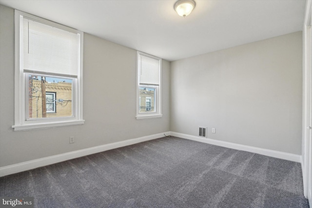 unfurnished room with dark colored carpet