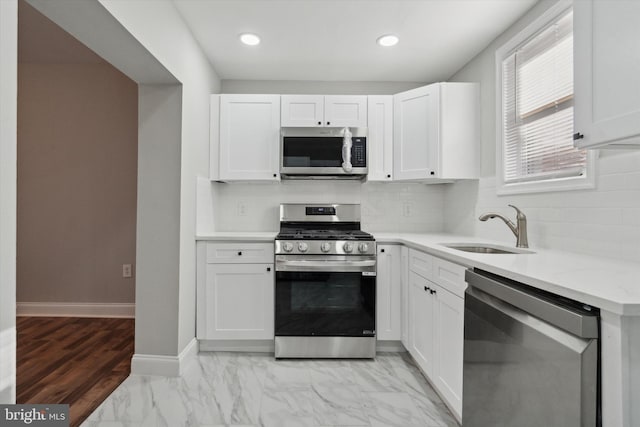 kitchen with tasteful backsplash, sink, white cabinets, and appliances with stainless steel finishes