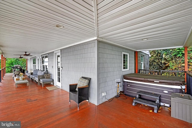 view of patio featuring a wooden deck, ceiling fan, a hot tub, and an outdoor living space