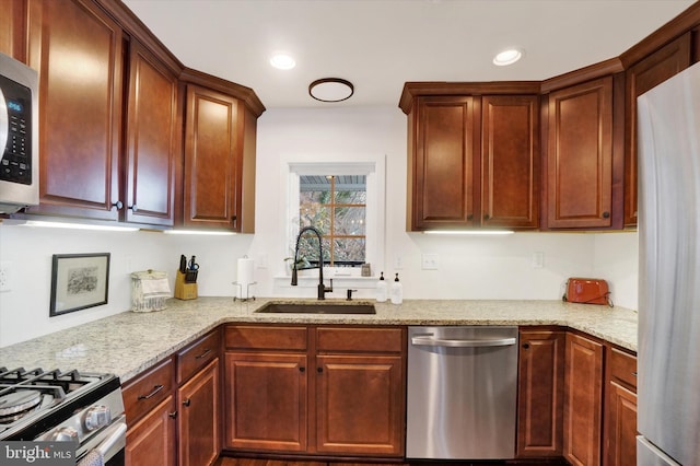 kitchen featuring appliances with stainless steel finishes, light stone counters, and sink