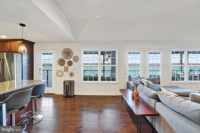 living room with dark hardwood / wood-style flooring, a water view, a healthy amount of sunlight, and lofted ceiling