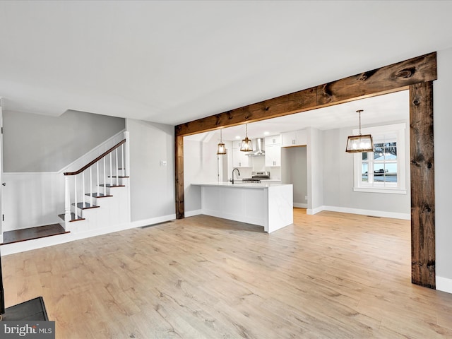 unfurnished living room with beam ceiling, sink, and light wood-type flooring