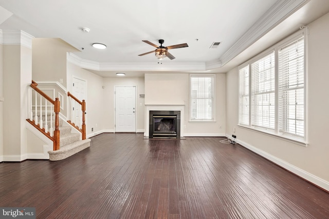 unfurnished living room with a raised ceiling, ceiling fan, dark hardwood / wood-style flooring, and crown molding