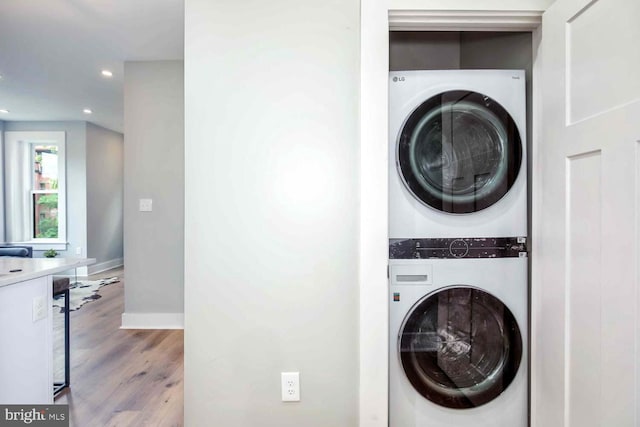 clothes washing area featuring stacked washer and clothes dryer and light wood-type flooring