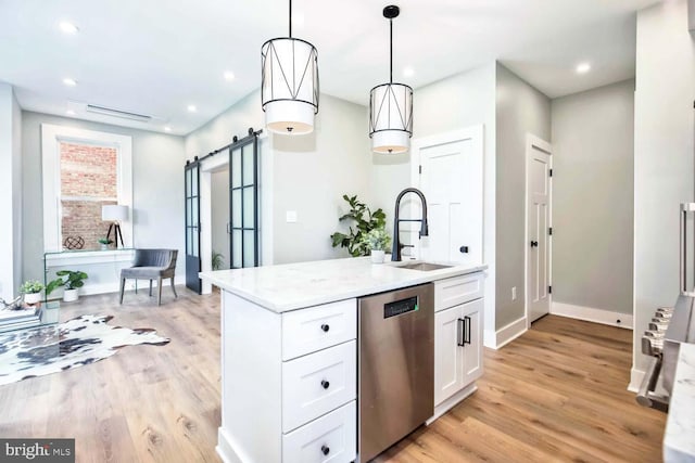 kitchen featuring stainless steel dishwasher, decorative light fixtures, a barn door, white cabinetry, and sink