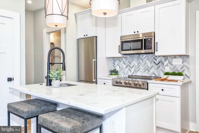 kitchen with white cabinets, stainless steel appliances, and a center island with sink