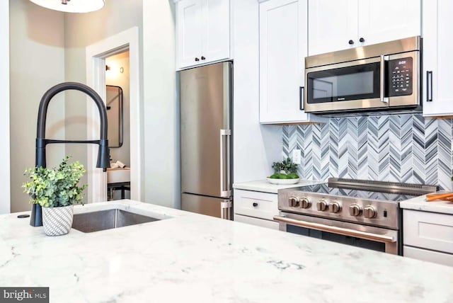 kitchen with light stone countertops, white cabinetry, tasteful backsplash, and appliances with stainless steel finishes