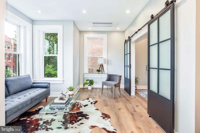 sitting room with french doors, a barn door, and light hardwood / wood-style floors