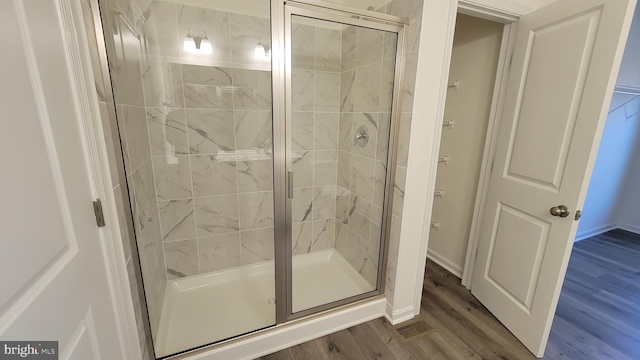 bathroom featuring wood-type flooring and a shower with shower door