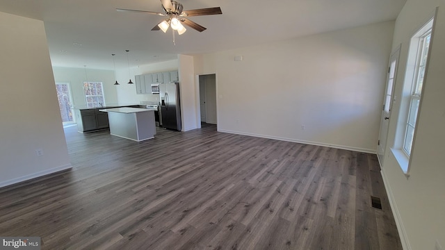 unfurnished living room featuring ceiling fan and dark hardwood / wood-style flooring