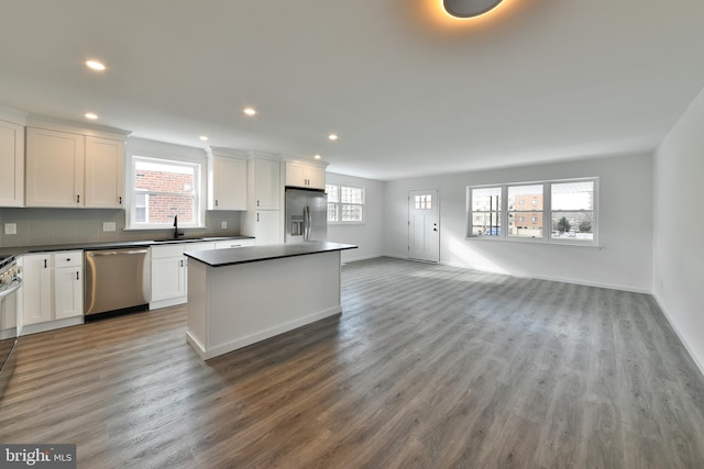 kitchen with appliances with stainless steel finishes, dark countertops, a center island, and white cabinets