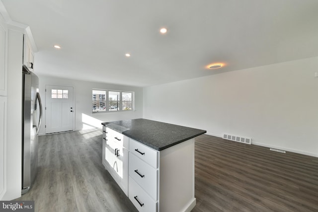 kitchen featuring visible vents, dark countertops, a kitchen island, white cabinetry, and stainless steel refrigerator with ice dispenser