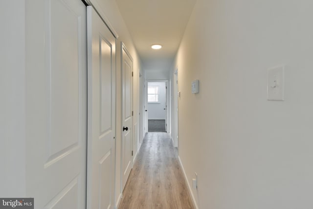 hall featuring light wood-style floors and baseboards