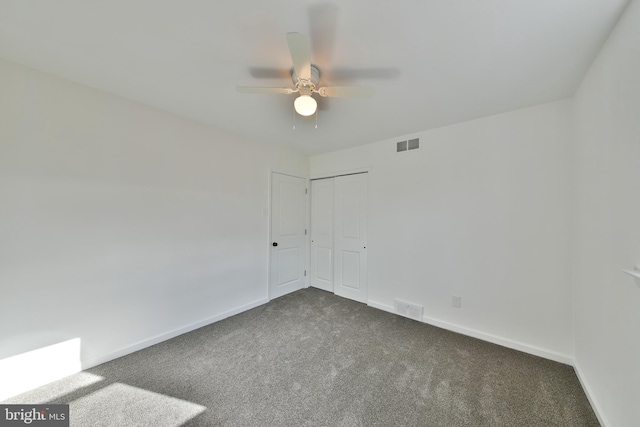 unfurnished room featuring baseboards, visible vents, and dark carpet