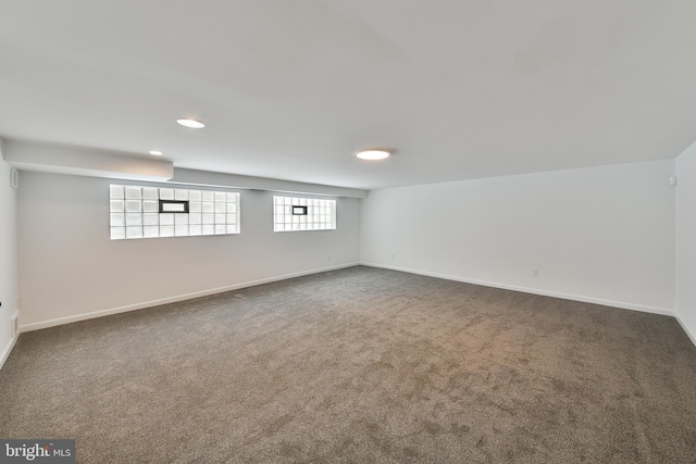 basement with baseboards, dark colored carpet, and recessed lighting