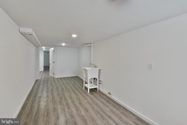 finished basement with a sink, light wood-style flooring, and baseboards