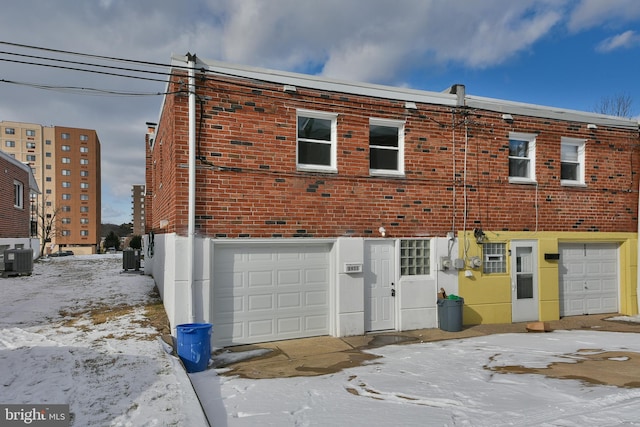 view of front facade featuring a garage, brick siding, and central air condition unit