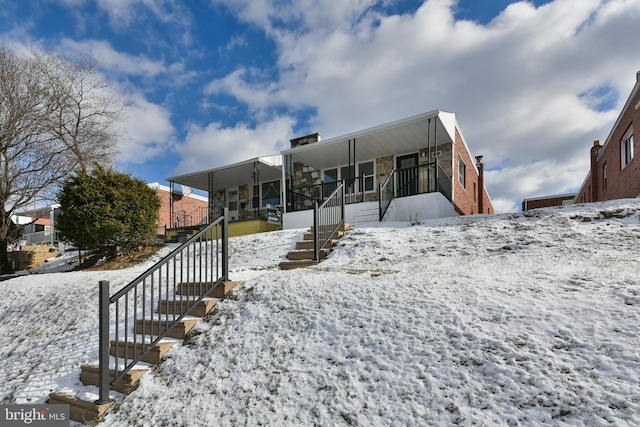 snow covered rear of property featuring a porch and stairs