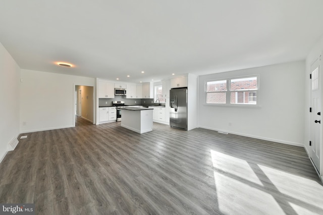 unfurnished living room featuring a sink, baseboards, and wood finished floors