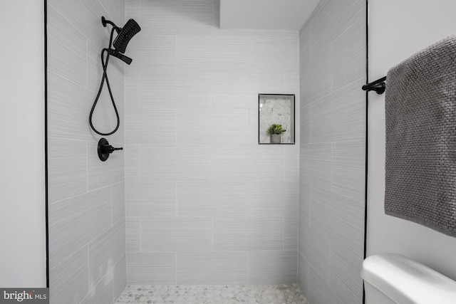 bathroom featuring a tile shower and toilet