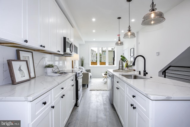 kitchen with white cabinets, stainless steel appliances, hanging light fixtures, and sink