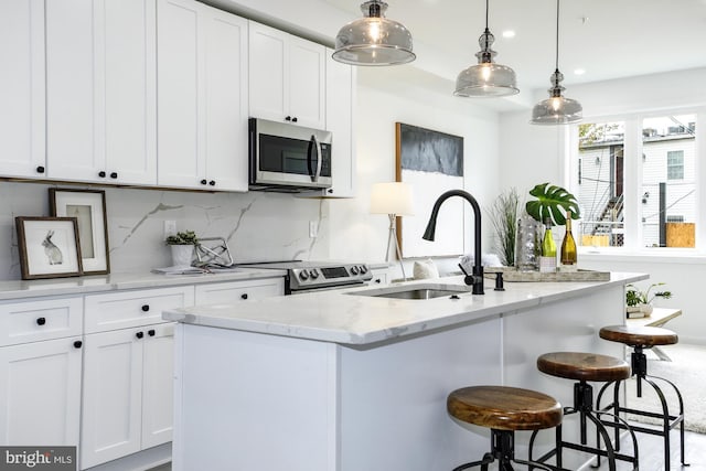 kitchen featuring a center island with sink, light stone countertops, white cabinetry, and appliances with stainless steel finishes