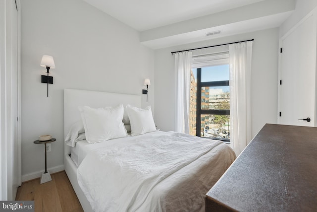 bedroom featuring visible vents, baseboards, and wood finished floors