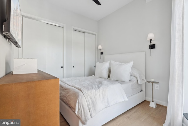 bedroom featuring a ceiling fan, two closets, baseboards, and wood finished floors