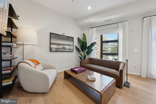 living room with recessed lighting, visible vents, baseboards, and wood finished floors