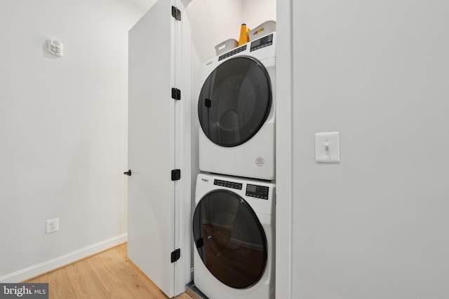 washroom with baseboards, laundry area, stacked washer / dryer, and light wood-style floors