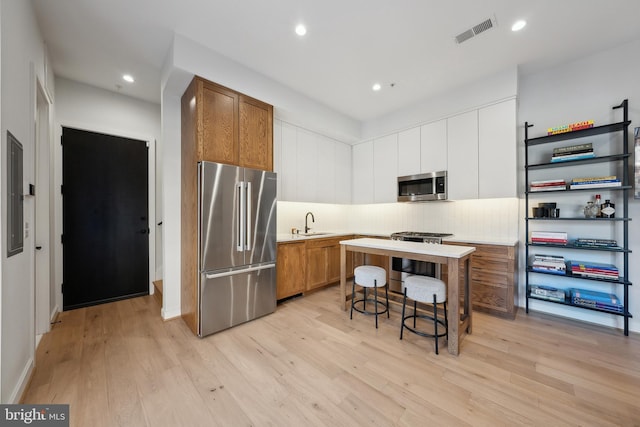 kitchen featuring a sink, visible vents, light countertops, appliances with stainless steel finishes, and light wood-type flooring