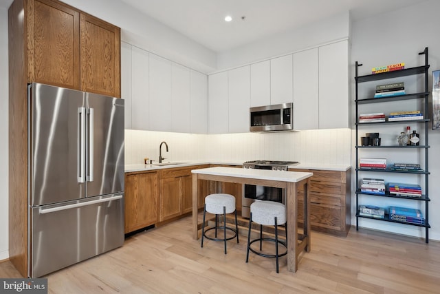 kitchen featuring stainless steel appliances, a sink, light countertops, and brown cabinets