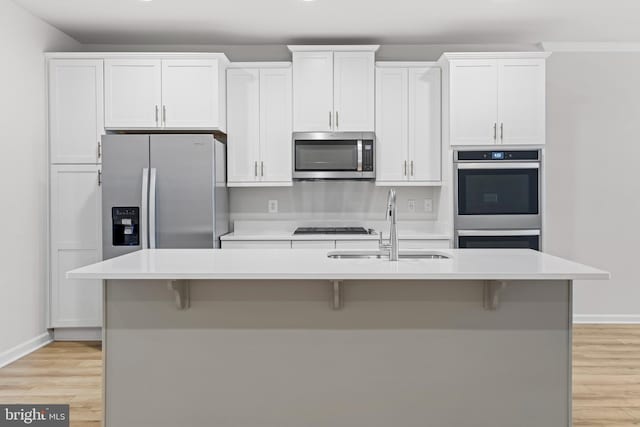 kitchen featuring white cabinetry, a kitchen island with sink, sink, and appliances with stainless steel finishes