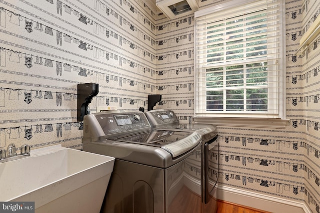 clothes washing area featuring hardwood / wood-style floors, washer and dryer, and sink