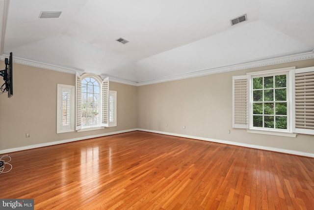 empty room with crown molding, vaulted ceiling, and light wood-type flooring