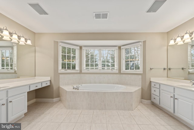 bathroom with tile patterned flooring, a relaxing tiled tub, and a healthy amount of sunlight