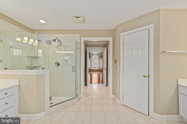 bathroom with walk in shower, vanity, and tile patterned flooring