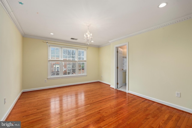 spare room featuring an inviting chandelier, crown molding, and light hardwood / wood-style flooring