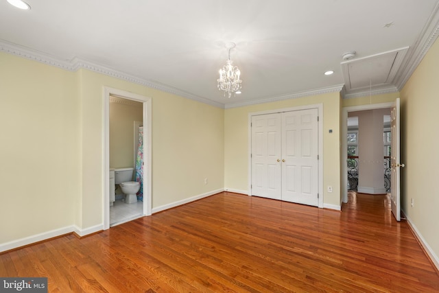 unfurnished bedroom with ensuite bathroom, wood-type flooring, ornamental molding, and a closet