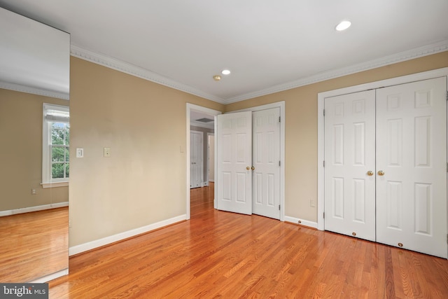 unfurnished bedroom with crown molding, two closets, and light wood-type flooring