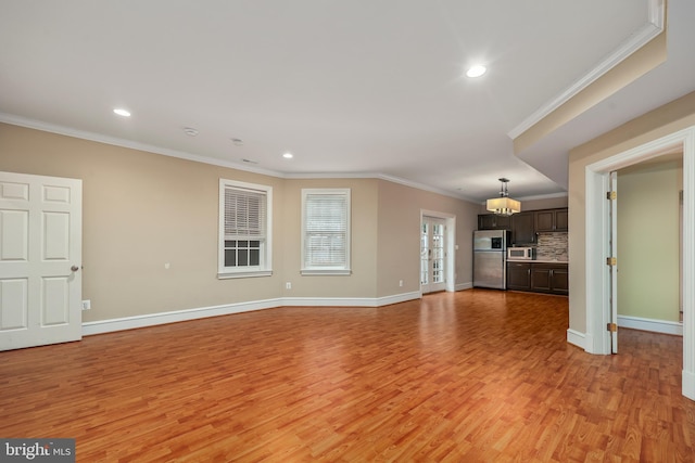 unfurnished living room featuring crown molding, an inviting chandelier, and light hardwood / wood-style flooring