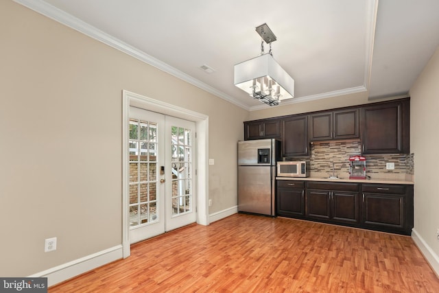 kitchen featuring decorative backsplash, dark brown cabinets, appliances with stainless steel finishes, and hanging light fixtures