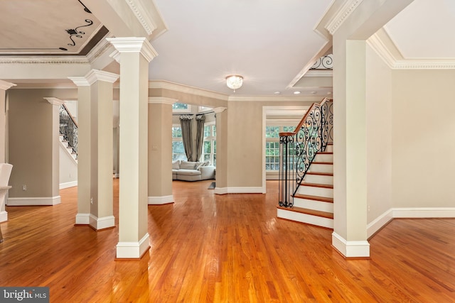 foyer entrance with crown molding, hardwood / wood-style flooring, and ornate columns