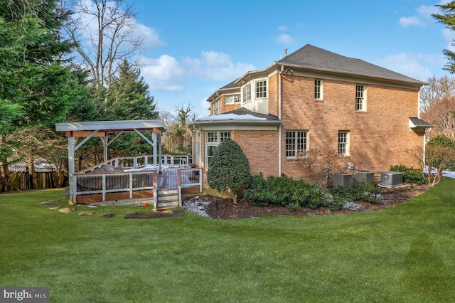 rear view of house featuring central AC, a deck, and a lawn