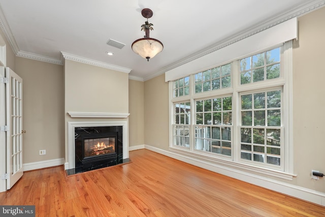 unfurnished living room featuring ornamental molding, a high end fireplace, and light hardwood / wood-style flooring