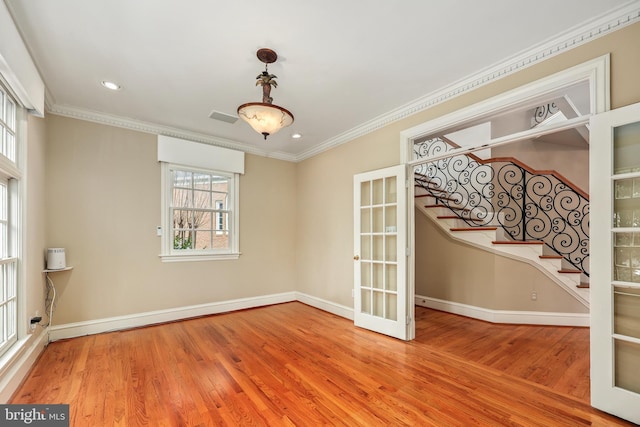 spare room with hardwood / wood-style floors, crown molding, a wealth of natural light, and french doors