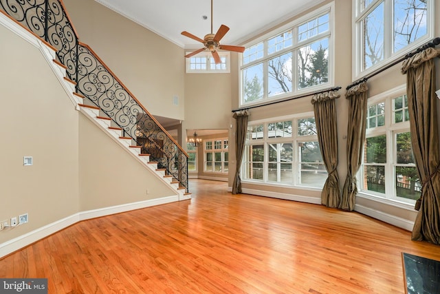 unfurnished living room featuring a towering ceiling, plenty of natural light, and light hardwood / wood-style flooring