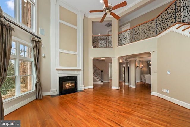 unfurnished living room featuring decorative columns, a towering ceiling, a wealth of natural light, and a high end fireplace