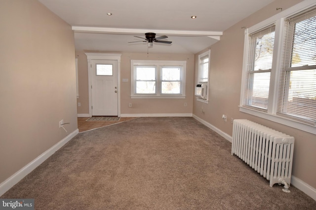 carpeted entryway featuring ceiling fan, beam ceiling, and radiator