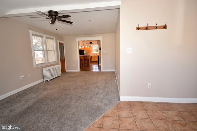 unfurnished living room with radiator heating unit, light colored carpet, and ceiling fan